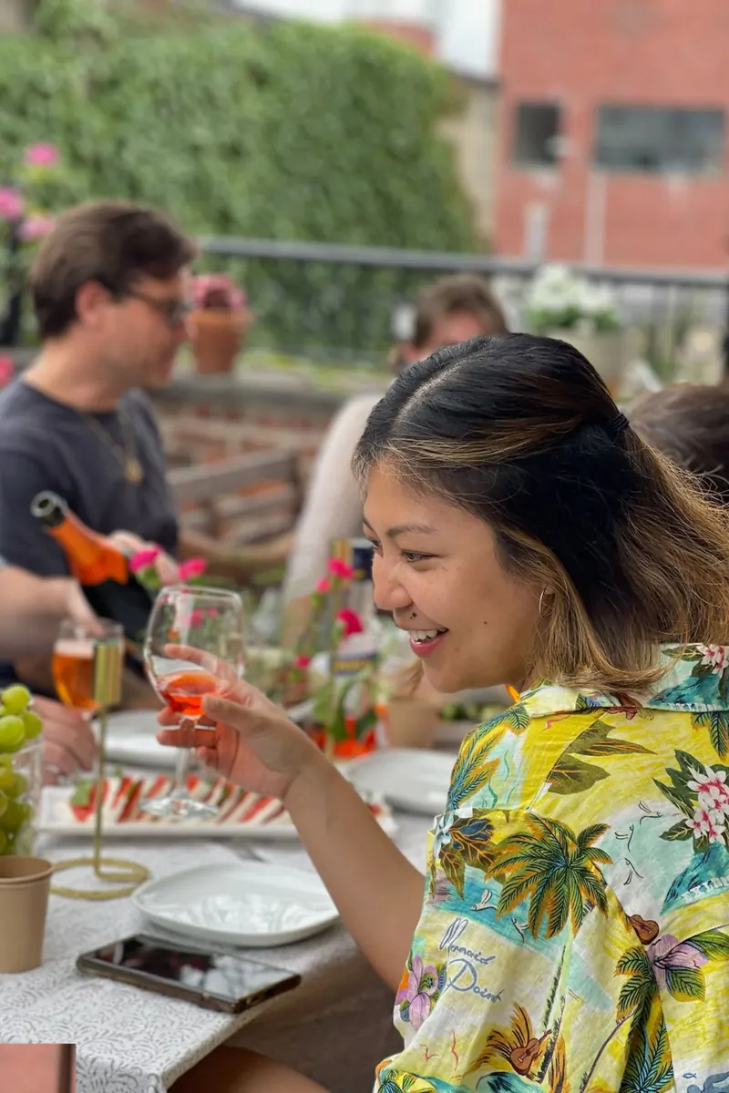 Guest laughing with a drink at a rooftop table at Green Boutique